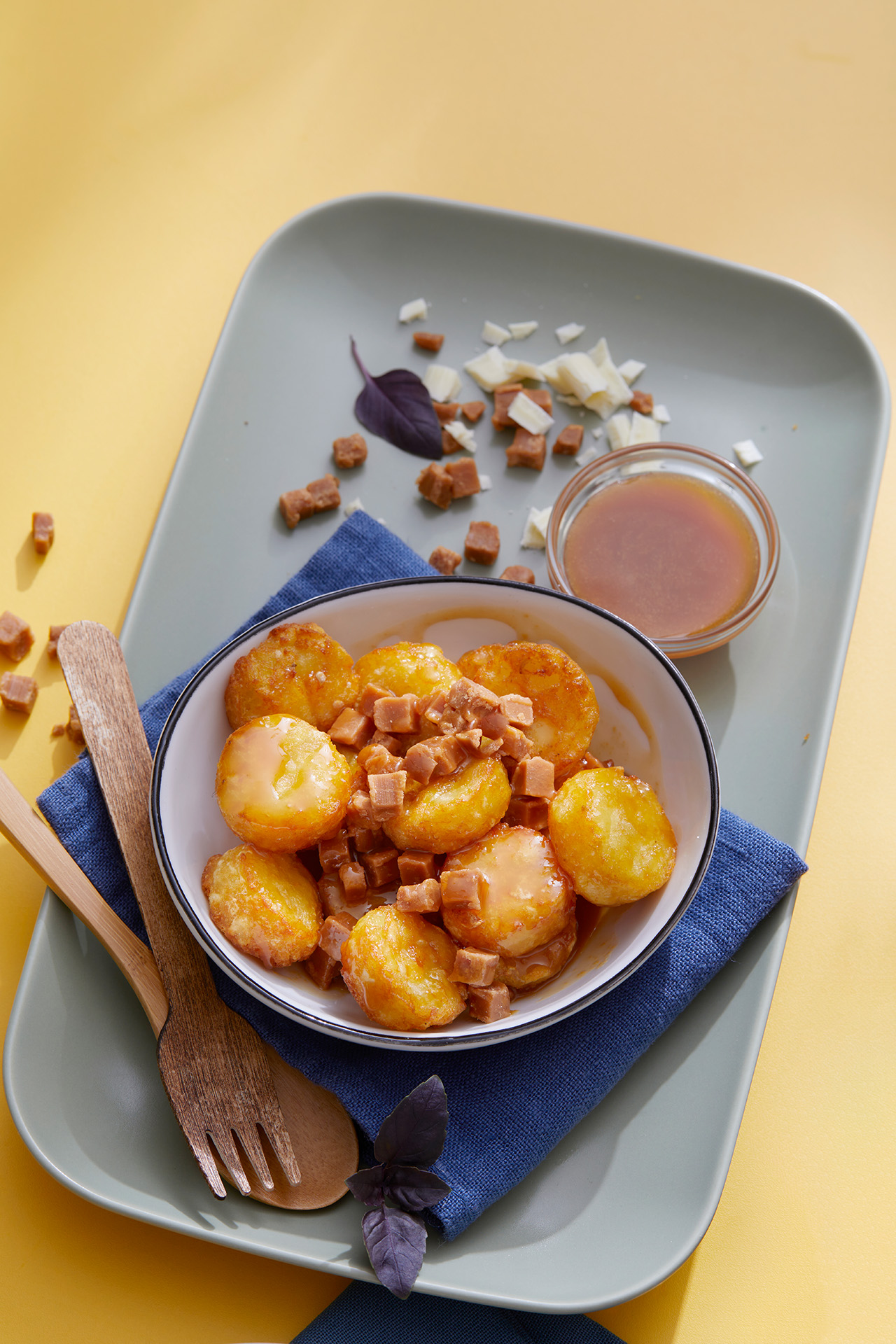 Mini Rösti Taler mit Karamellsauce und Karamellstückchen auf einem Teller.